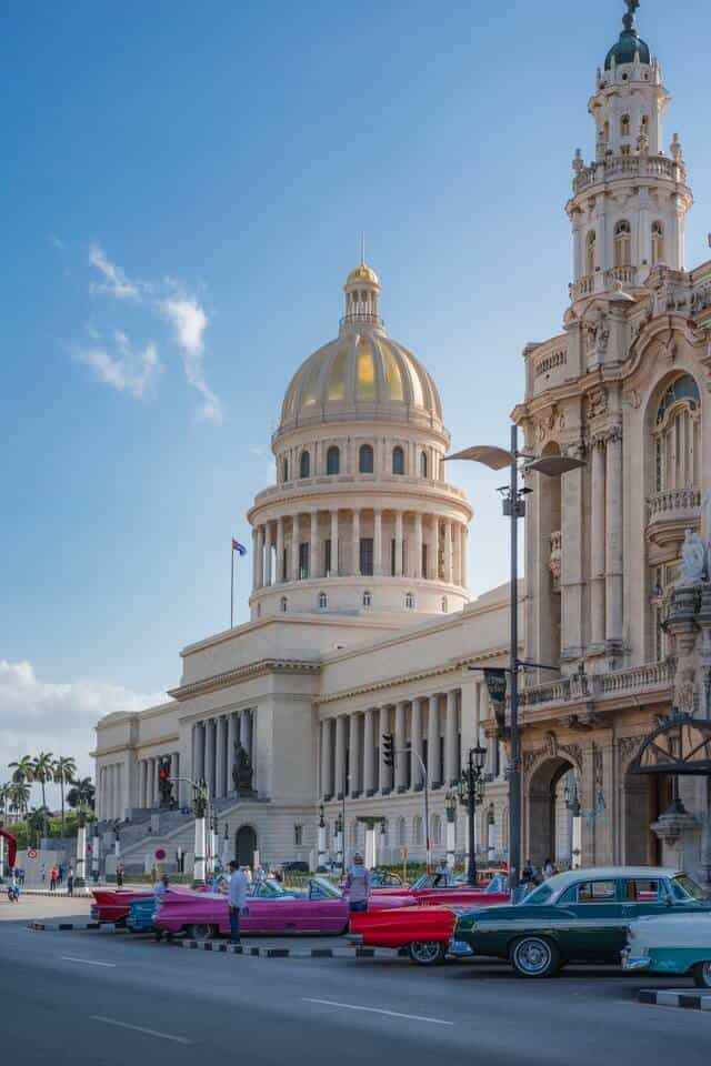 Capitol Building and Grand Theater in Havana Cuba with colourful classic cars parked on the street in front