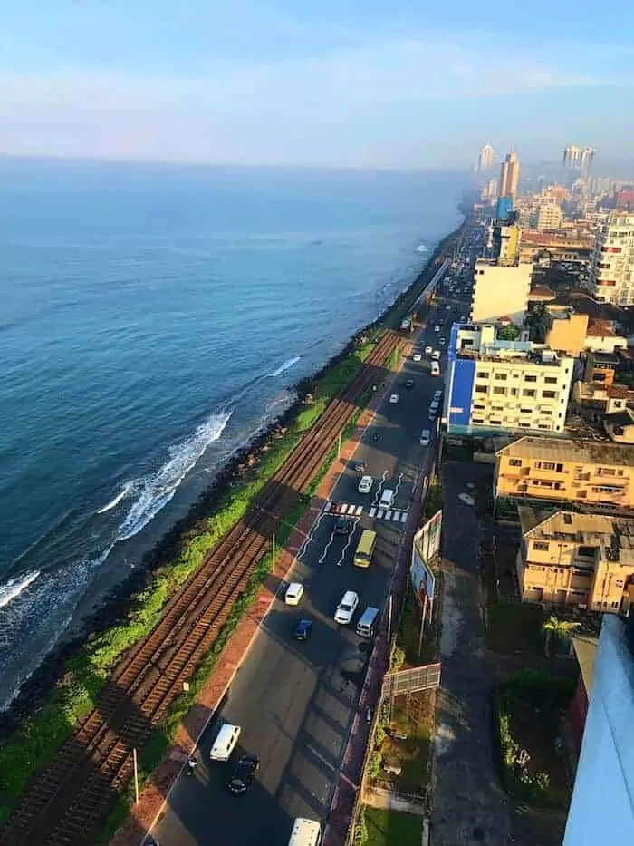 Colombo from above with the city on one side, road down the middle next to train tracks and the ocean on the left.