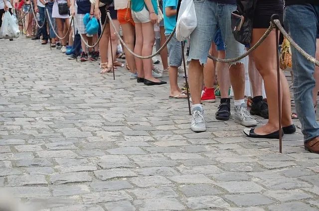 People queing behing a rope on a cobbled street