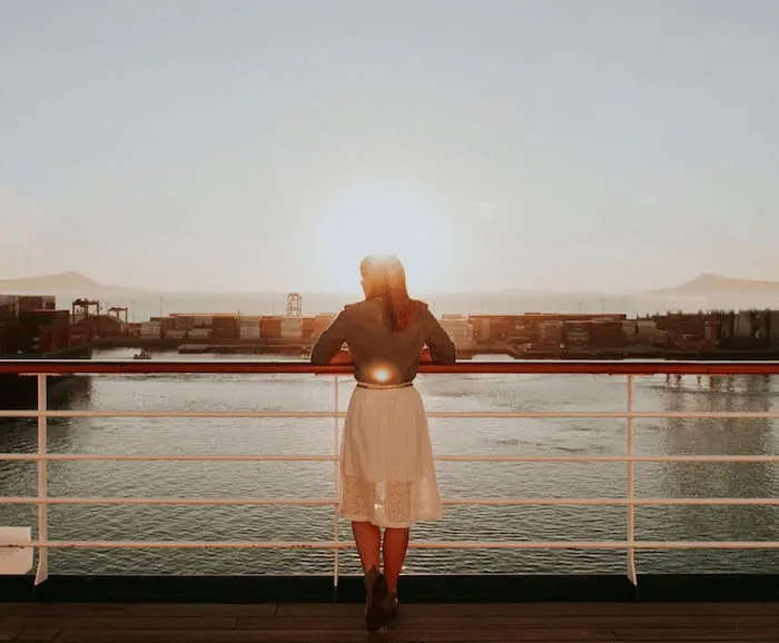 woman stood on a cruise ship balcony for Solo travel on a cruise