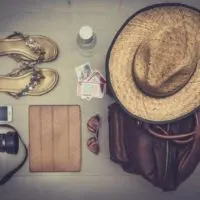 Cruise Packing List flatlay - camera, hat, suitcase and flip flops