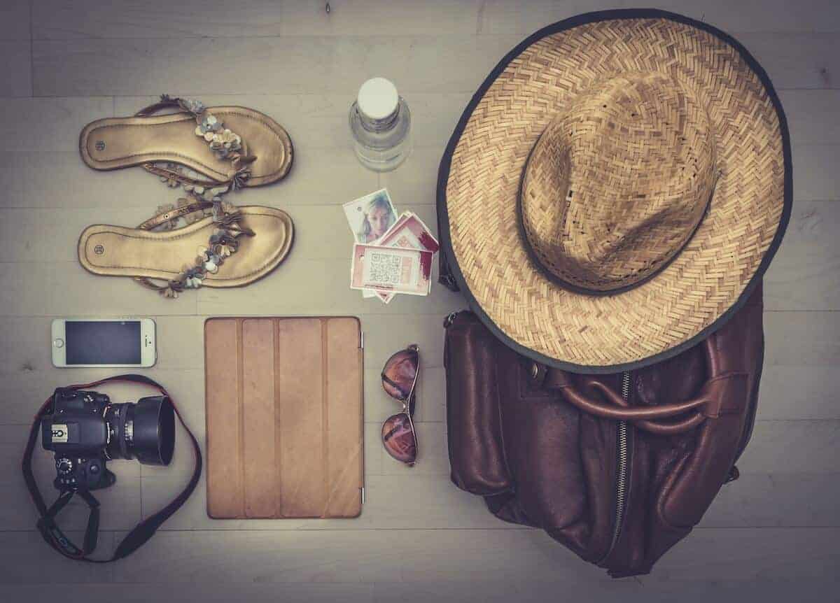 Cruise Packing List flatlay - camera, hat, suitcase and flip flops