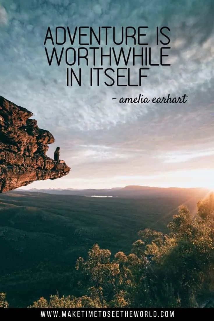 Adventure is Worthwhile in itself - a quote about adventure pin image of a woman sat on a high rocky outcrop overlooking a national park just after sunsrise