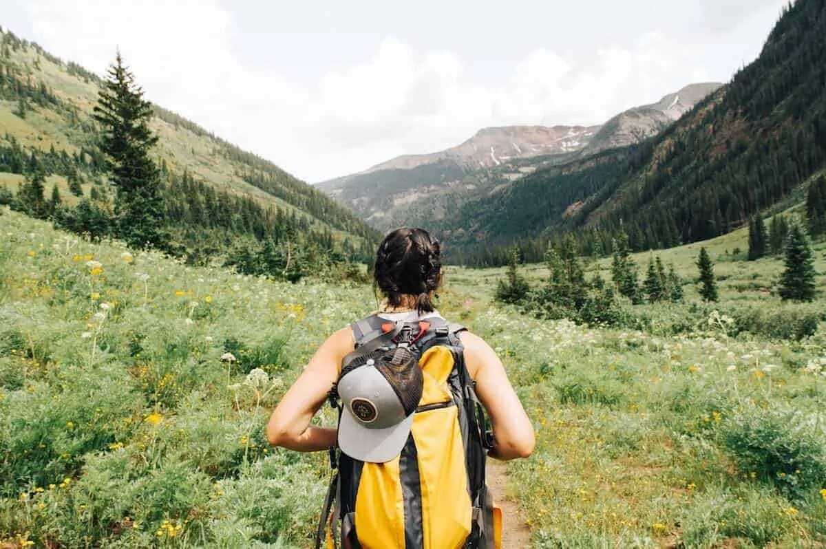 Eco Friendly Gifts for Travel - female traveler looking out across a green field wearing a backpack