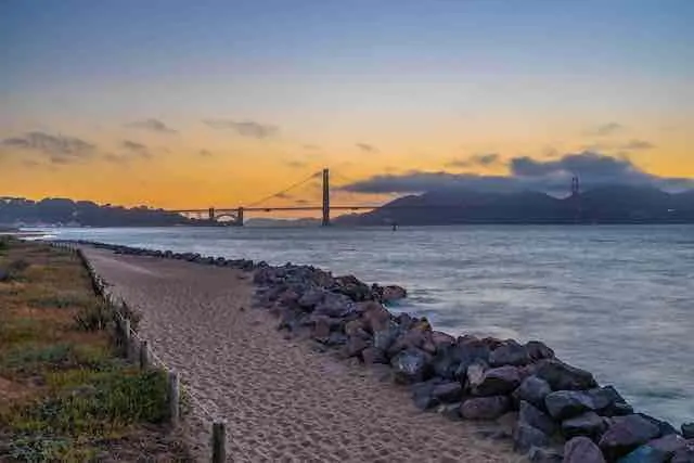 Pathway next to the water in Crissy Field San Francisco with view of the Golden Gate Bridge and sunset in the background