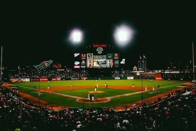 View of the field at Oracle Park at night with the scoreboard flanked by two floodlights which are turned on
