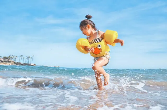 Kid wearing floaties paddling at the beach