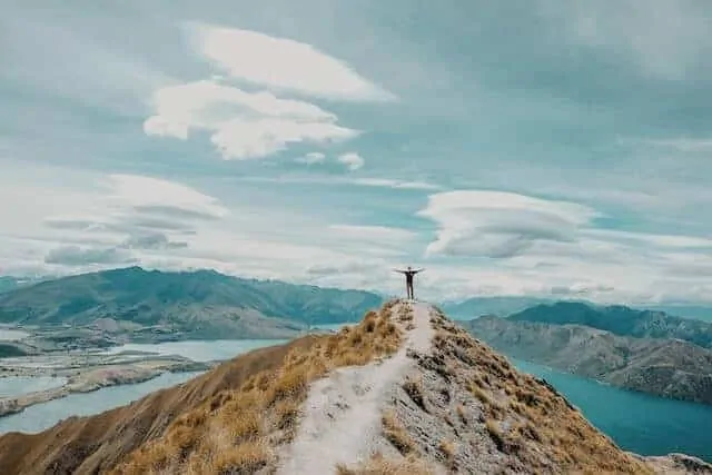 Person standing with open arms at Roy's Peak Lookout, New Zealand