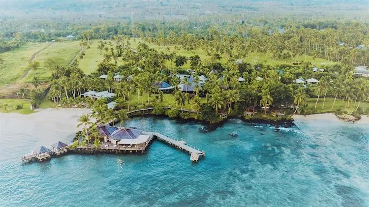 Areial View of Sinalei Reef Resort & Spa with ocean in the foreground, resort on the edge of the water and lush green palm tress behind