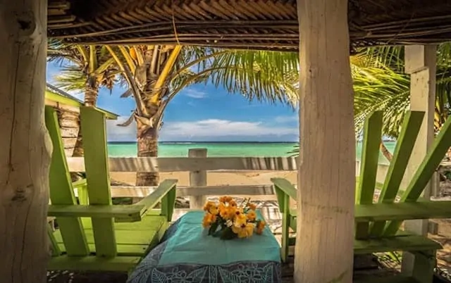 Looking out to the ocean from inside a beach Fale with green deck chairs either side of the frame