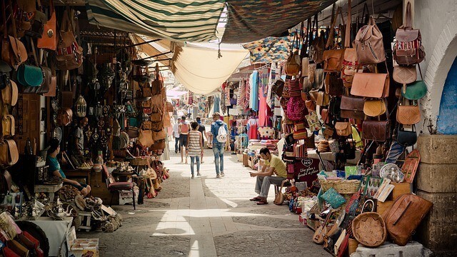 Inside the souk in marrakech with traders stalls either side of the frame and people walking away down the center