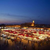 Things to do in Marrakech header image - view over the market square at night with the tents lit up and surrounded by people