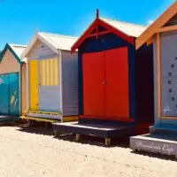 The Best Day Trips from Melbourne & Weekend Getaways in Victoria Cover Photo - Close up of 4 multi coloured bathing boxes on the beach
