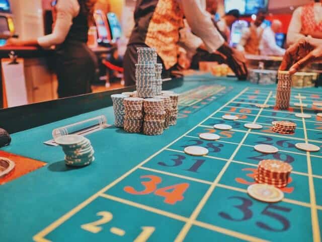 Dice table with chips piled high next to the board and chips laid across various numbers on the board