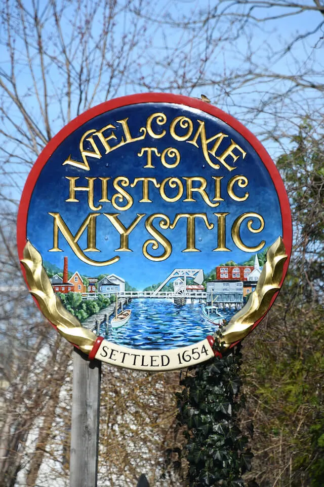 Round sign stating "Welcome to Historic Mystic, Settled 1654" in Mystic Connecticut