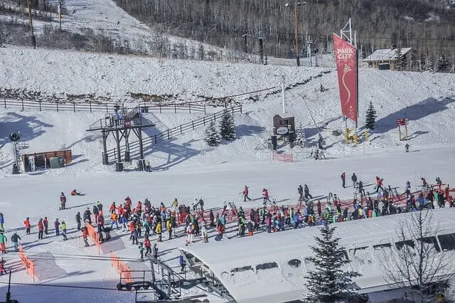 Base of Olympic Park Ski resort in Utah with lines of people on skis and snowboards queing for the ski lift
