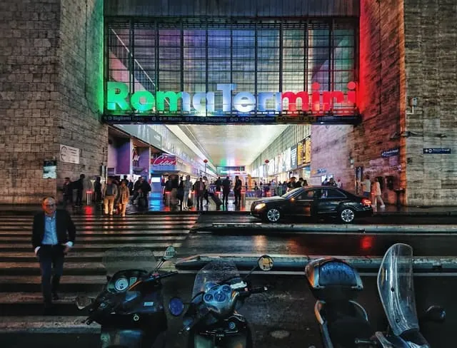 Facade of Roma Termini (Rome Train Station) bathed in a strip of green, white and red light (the colours of the Italian Flag)