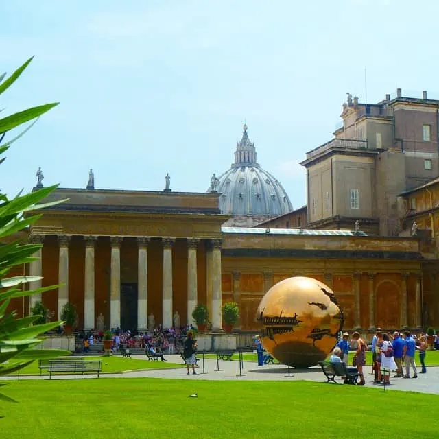 The gardens inside the Vatican Museum with green grass, golden globe and st Peters Bascilica in the background