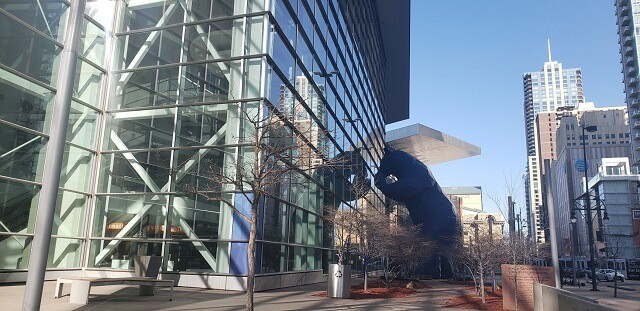 40 foot blue bear looking into a clear glass square building