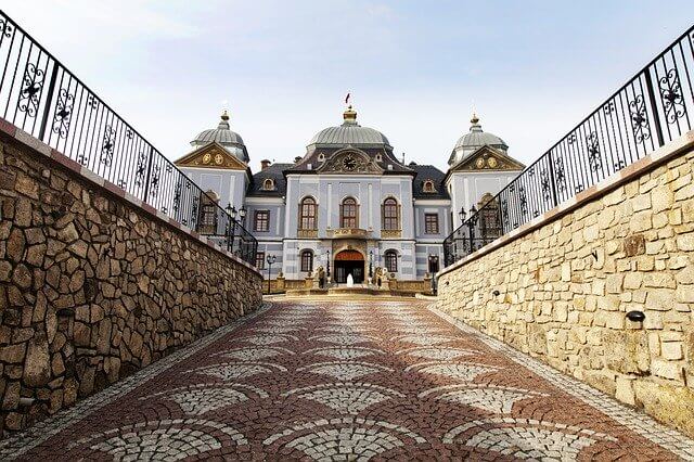 View looking up towards the Halic Castle - a white building with three sections topped with green domes with gold spires in Galicia