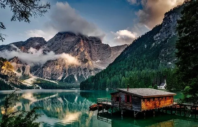 Italian lake and mountain compbination with a wooden hut in the foreground standing on stilts in the lake