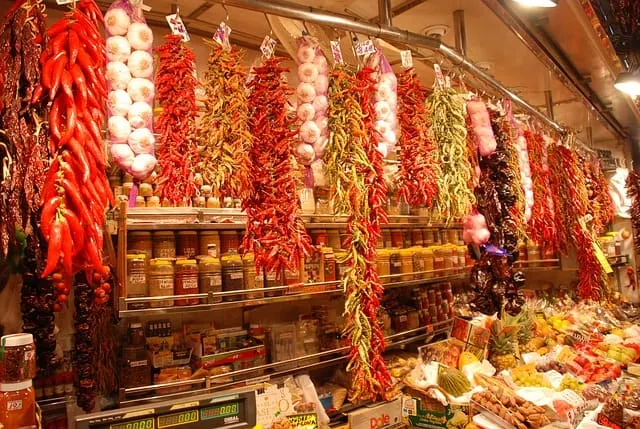 Food stall with garlic and chilli hanging from rails close to the ceiling in Barcelonas La Boqueria Market