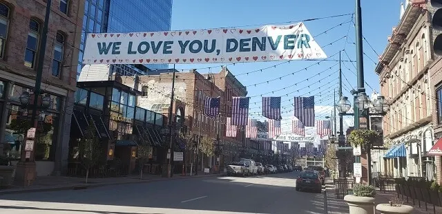 Larimer Square covered in bunting and festival lights with a banner stating 'We Love You Denver'