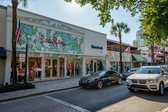 Colourful storefront on Las Olas Boulevard with a black car parked in front and palm trees on the sidewalk