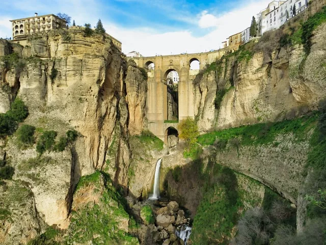 The famous 3 Arch Bridge in Ronda, perched high on the clifftop and water flowing 100 meters below it down towards the valley floor