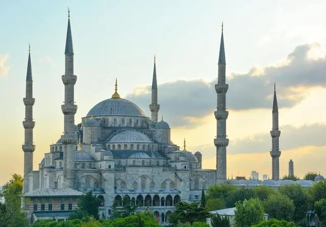 The impressive domed buildings of the Blue Mosque surrounded by 5 Minaret Towers from a distance at dusk
