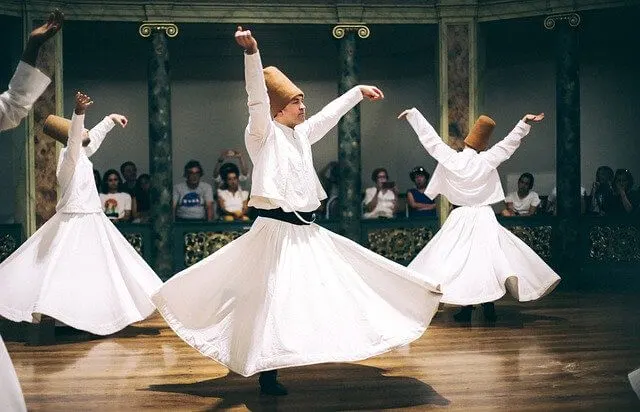 Whirling Dervish Performance featuring three Dervishes in white long skirts and tops with red fez style hats