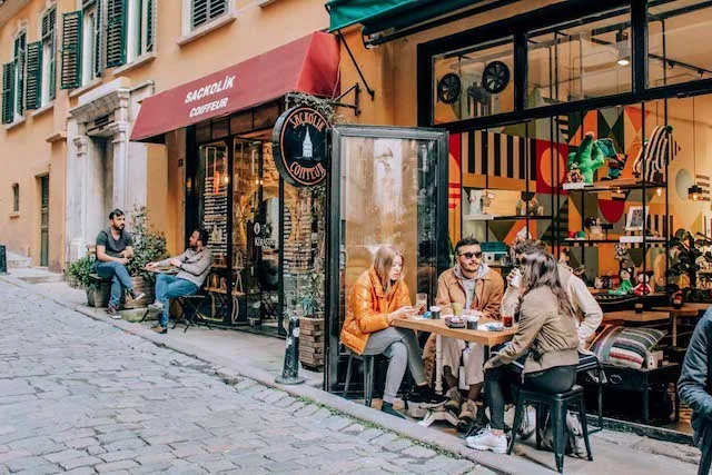Cobbled street of the Karokoy neighbourhood featuring two restaurants with tables outside on the sidewalk with people eating and drinking