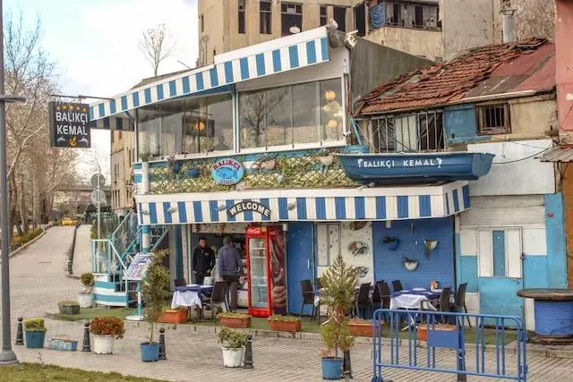 A fish restaurant near the Galata Bridge with a blue and white striped canopy above the first and second storeys