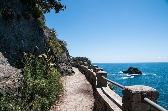 Narrow coastal path between the Cinque Terre villages with the rock face on the left and the ocean below the path on the right