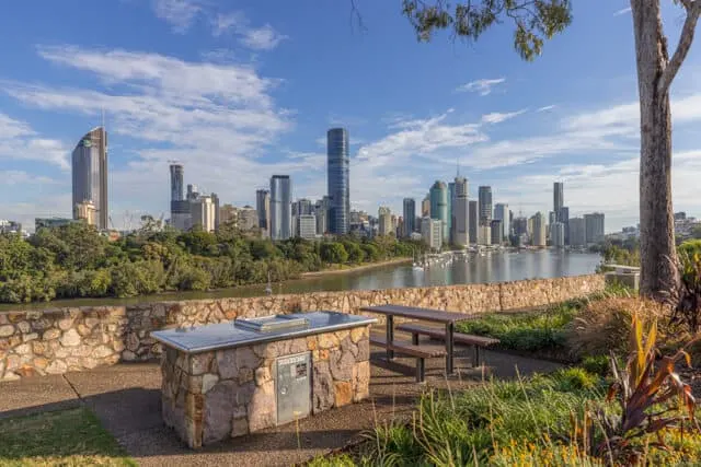 Outdoor BBQ area next to a picnic bench with Brisbanes skyline in the distance