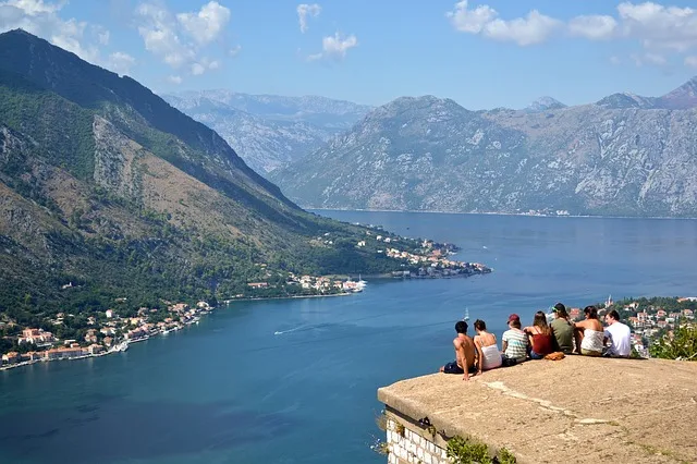 People sitting with their backs to the camera looking out over Kotor Bay below