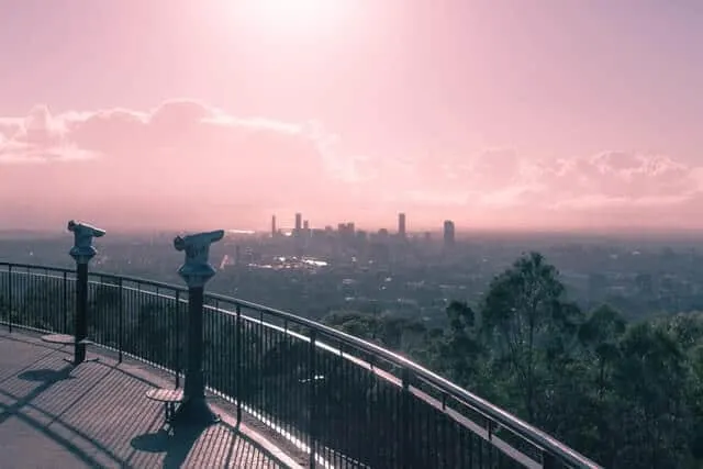 Mount Coot Tha lookout with Brisbane city skyline in the distance under a pink sunset sky