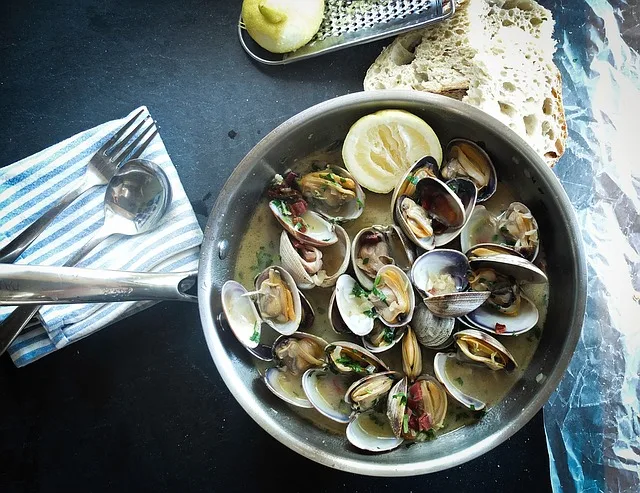 Muscles in a pan with a cream sauce and lemon wedge