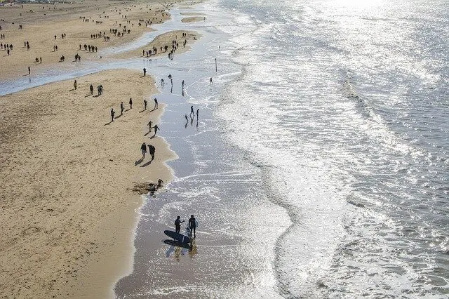 Aerial shot of a busy beach in Holland with people standing along the shoreline