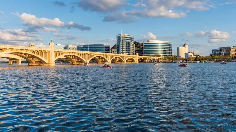 Arched Bridge over the water with city skyline in the background at Mill Ave and Tempe Beach Park