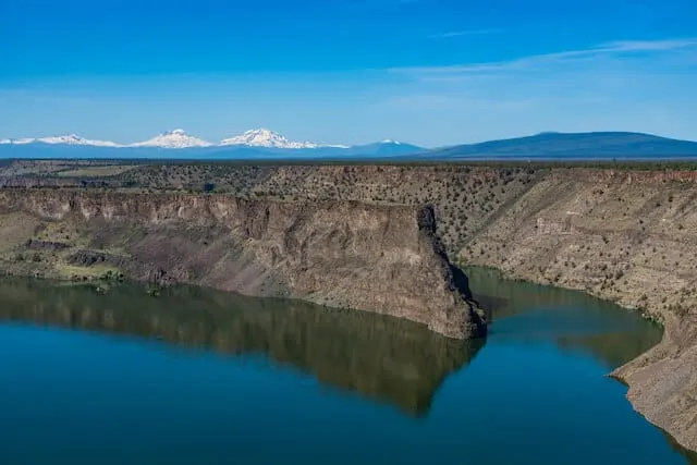 Dark blue body of water with a large tall rock standing at its centre