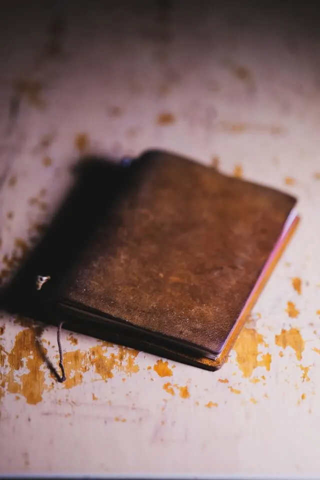 Brown Leather journal in focus on a wooden table painted white with the wood showing through