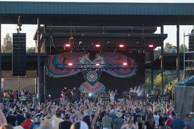 Packed outdoor entertainment venue with a eagle mural at the back of the stage and a live band perfomring to the crowd