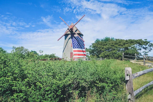 The Old Mill adorned with the american flaf surrounded by lush greenery