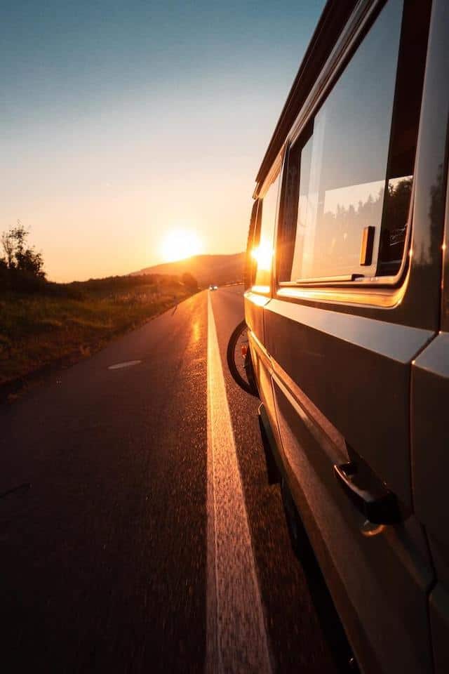The Ultimate Travel Playlist pinnable image of a campervan driving into the sunset