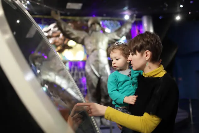 Woman holding a small child while touching an exhibit