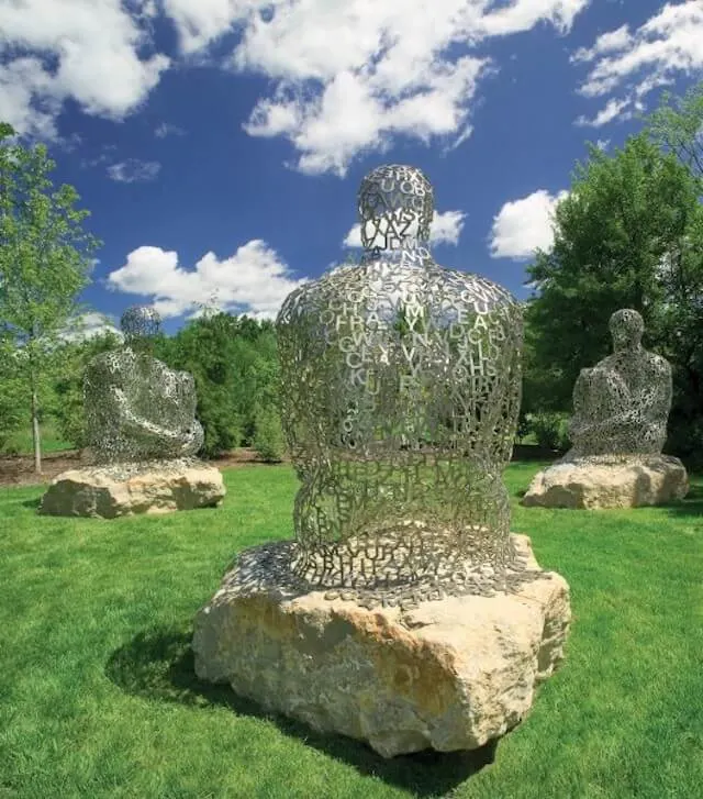 Frederik Meijer Gardens and Sculpture Park showing three metal statues of people sitting on rocks
