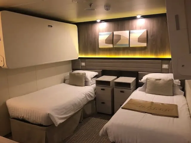 Inside cabin on Britannia Cruise ship with twin beds and bedside tables in between the beds