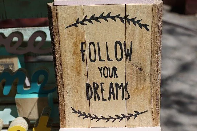 Wooden board with black lettering that says 'Follow Your Dreams'
