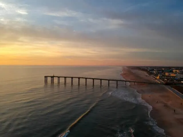 Long wooden pier stretching out into the ocean at sunset